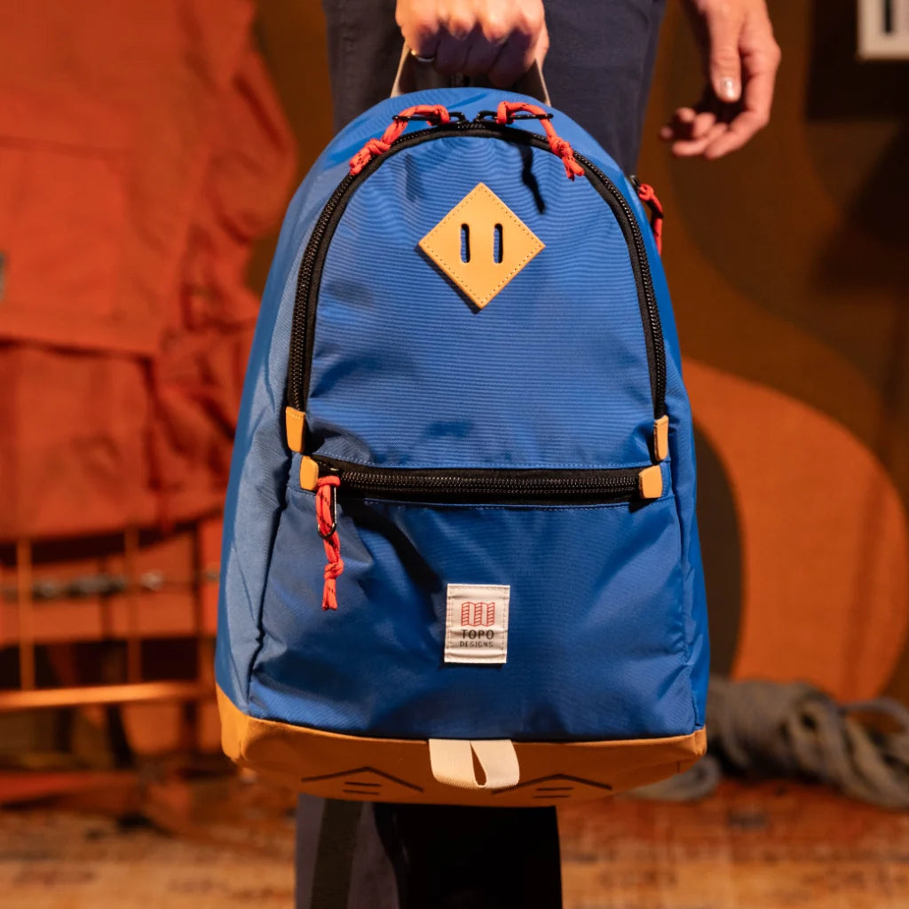 General model view of Topo Designs Classic Teardrop Backpack in "Classic Blue" being held by top handle.