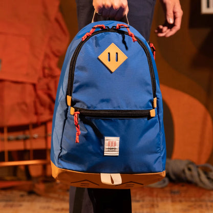 General model view of Topo Designs Classic Teardrop Backpack in "Classic Blue" being held by top handle.