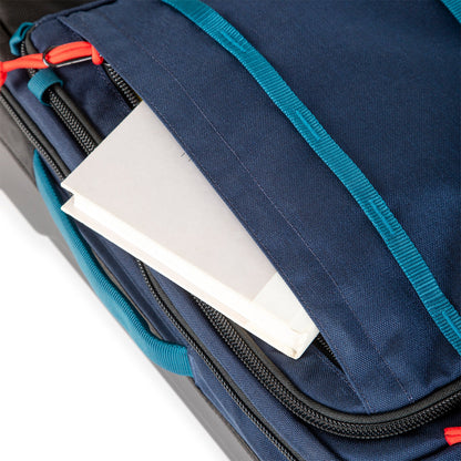 General shot of front zipper pocket on Topo Designs Global Travel Bag Roller durable carry-on convertible laptop rolling backpack suitcase in Navy blue.